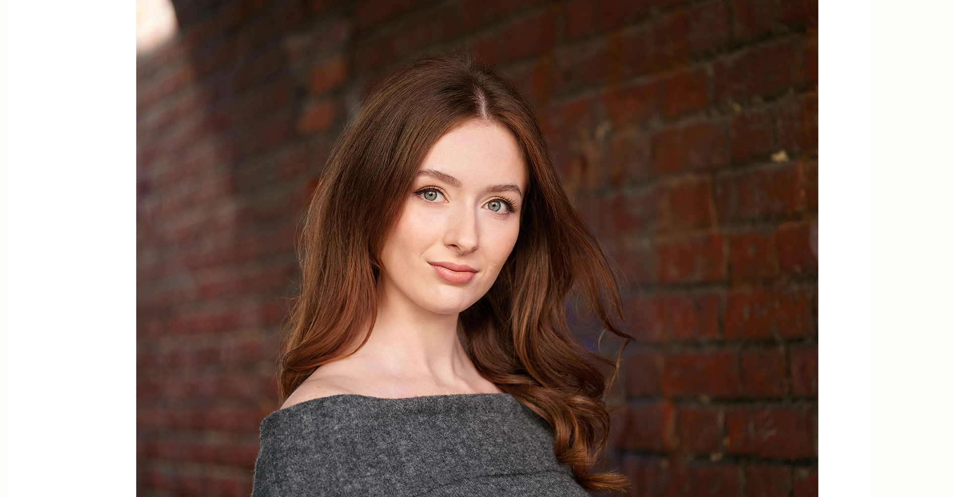 Red hair actress side on front of brick wall in natural light